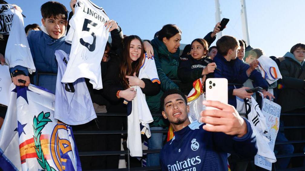 Jude Bellingham poses for photos with fans during training