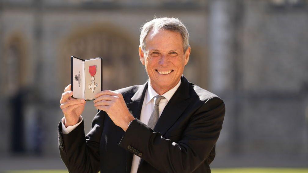 Alan Hansen poses with his MBE award