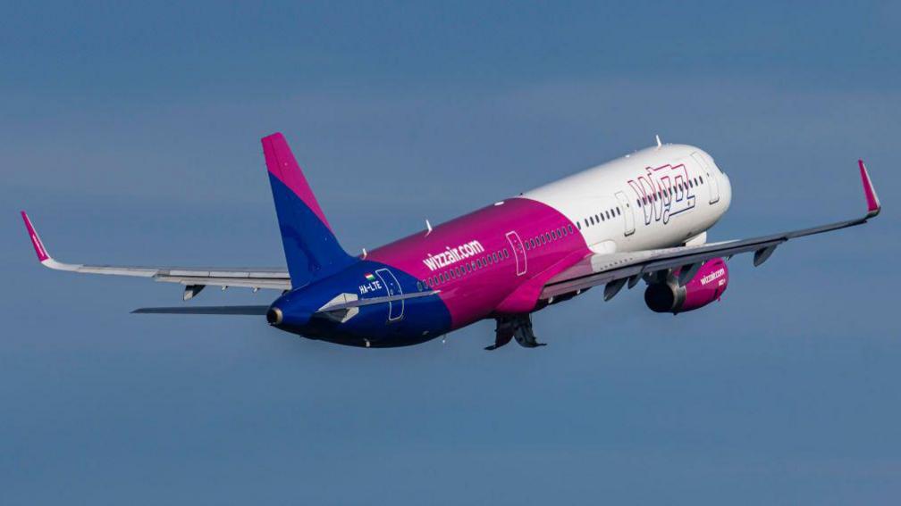 Wizz Air Airbus A321 flying against blue sky