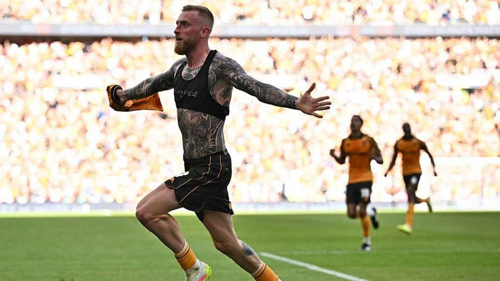 Hull City strike Oli McBurnie with his shirt off showing a torso and arms covered in tattoos runs away to celebrate his winnin goal against Middlesbrough