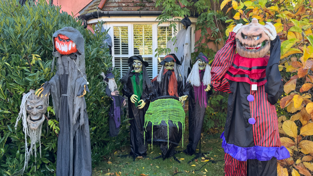 A group of Halloween fixtures outside Mr Wright's home, including three witches and two figures with pumpkins for heads.