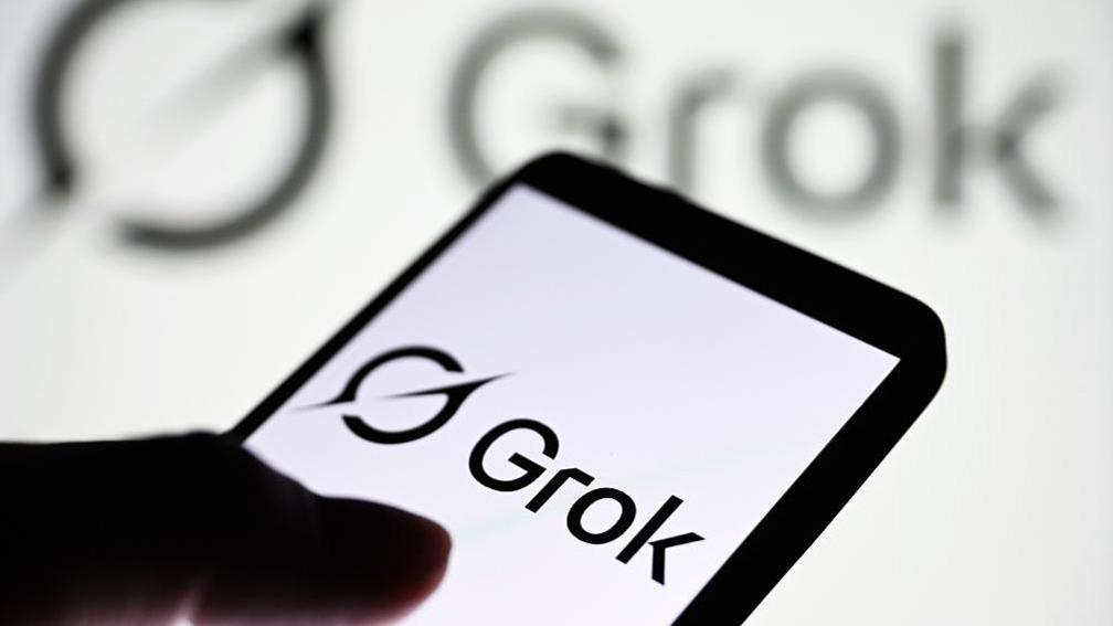 Grok logo displayed on a smartphone, with it's logo shown on a blurred, larger backdrop behind it. 