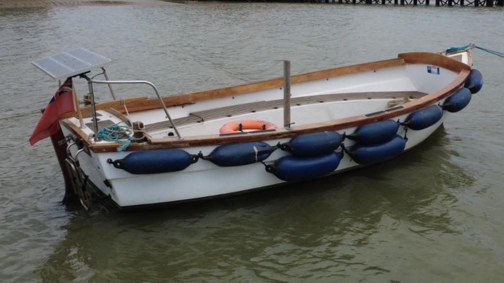 The new boat is small and white with navy floats tied to its side.