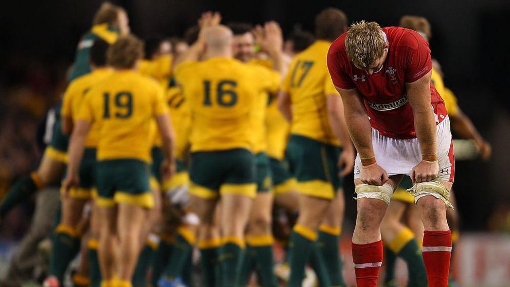 Wales lock Bradley Davies with the Wallabies celebrating in the background