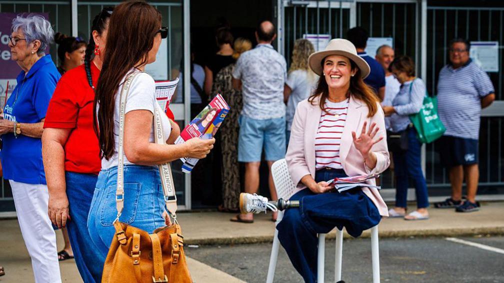 Federal Labor Candidate for Dickson, Ali France (R), hands how to vote flyers at a pre-polling centre at the Northern Brisbane seat of Dickson on May 2, 2025.