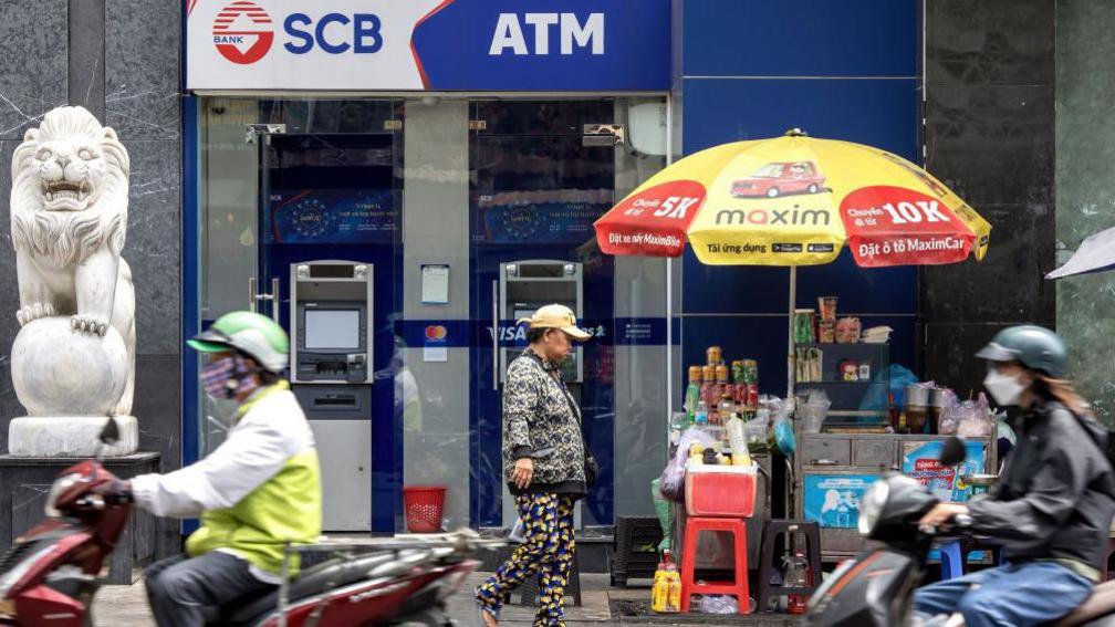 Motorbikes speed past a branch of Saigon Commercial Bank (SCB) in Ho Chi Minh City, Vietnam, on Wednesday, April 17, 2024.