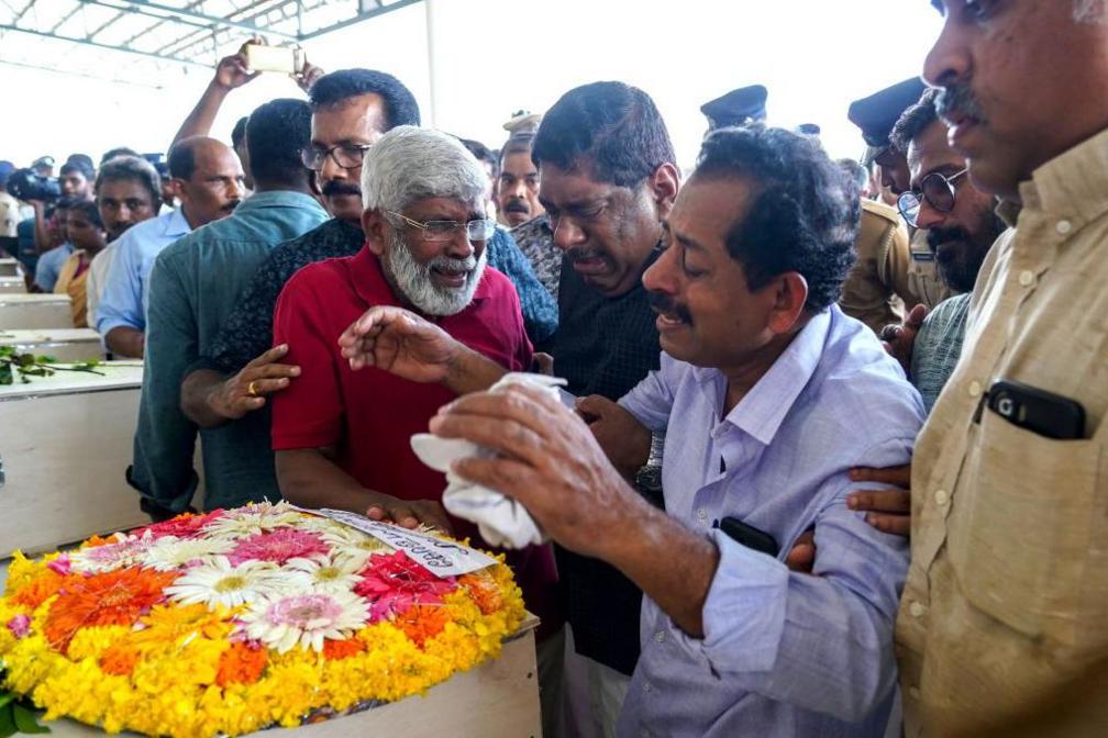 Relatives mourn near the deceased after the coffins' arrival on an Indian Air Force plane from Kuwait at the Cochin International Airport in Kochi on June 14, 2024.