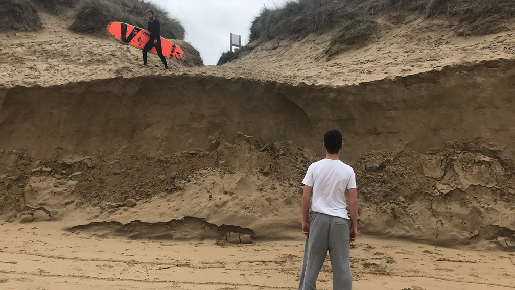 Man standing in front of sand cliff