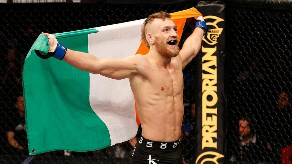 Conor McGregor holding the Irish tricolour after winning a fight