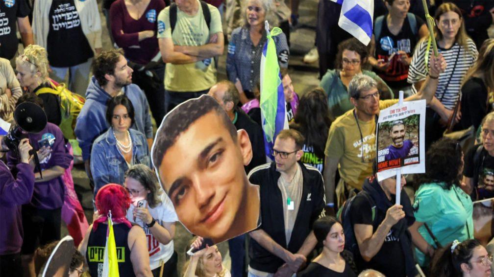 Protesters hold up a photo of Edan Alexander