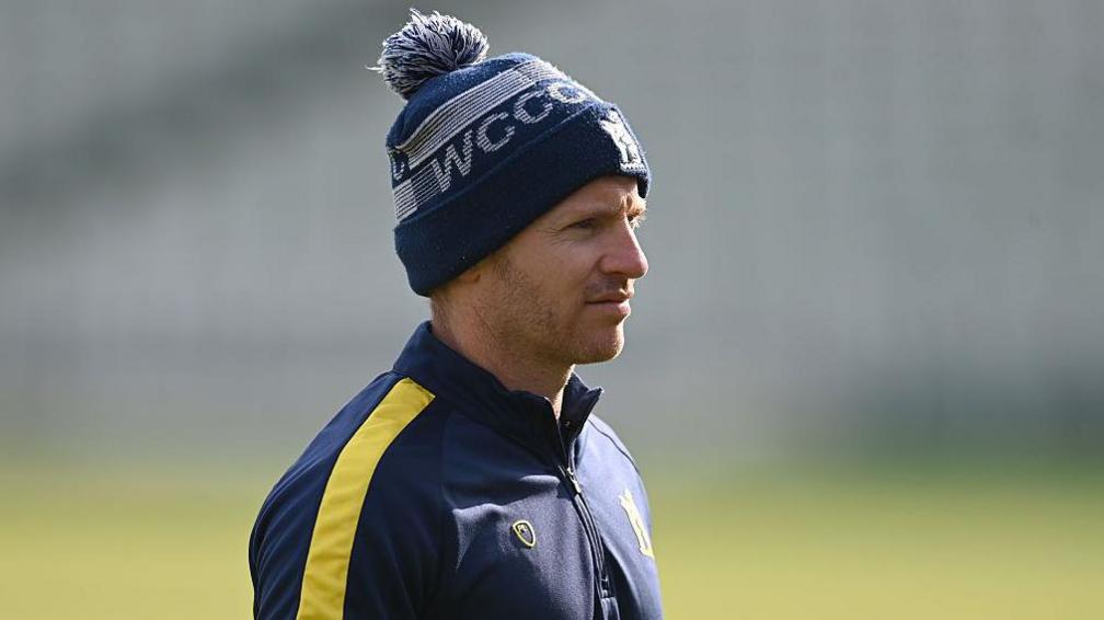 Ian Westwood in a Warwickshire bobble hat looks on during a pre-match warm-up session