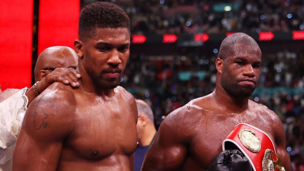 Anthony Joshua looks dejected with a smiling Daniel Dubois beside him