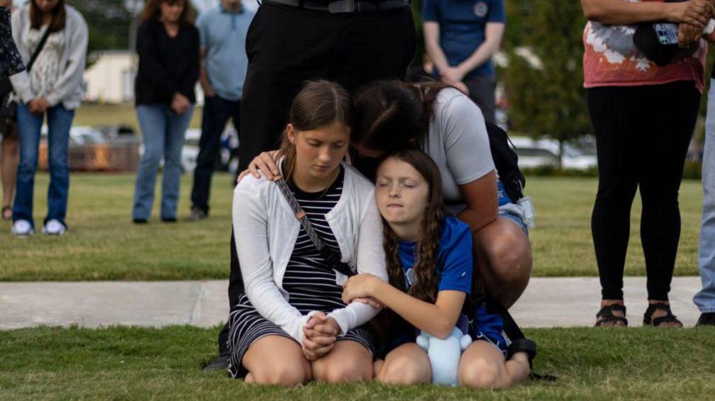 A mother comforts her children at the evening vigil