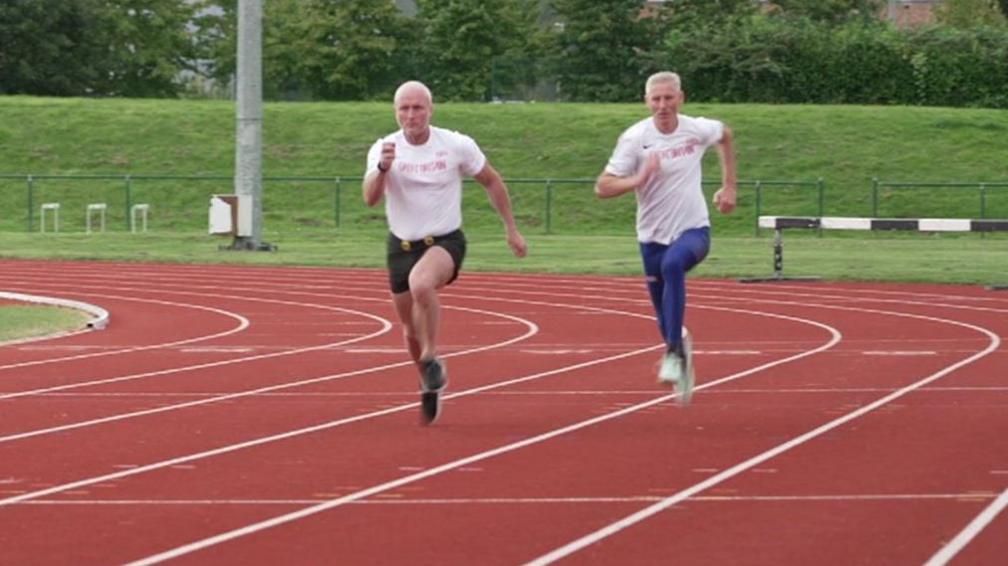 Darren Scott and his running partner Mike in full sprint at an athletics track in St Helens 