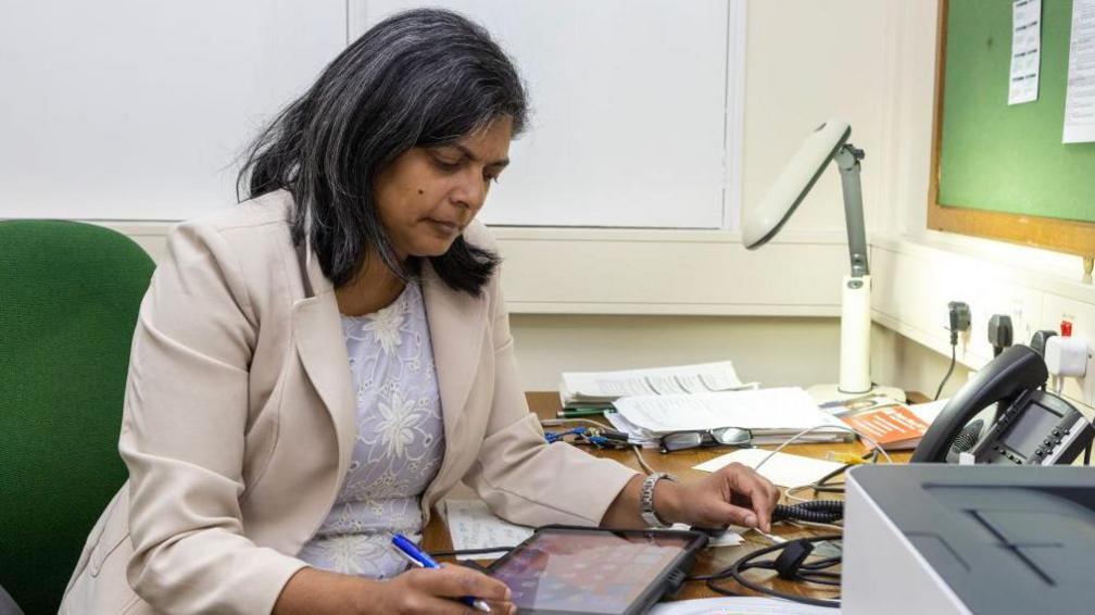 Rupa Huq at work on an iPad in her office 