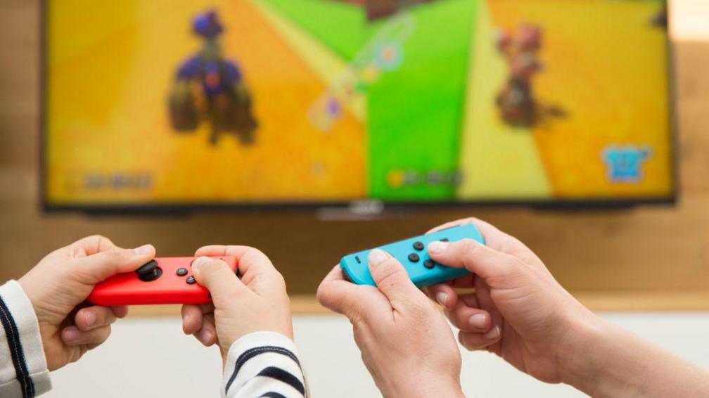 Hands of people playing the Nintendo Switch.