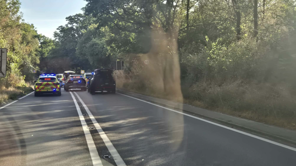 Police cars can be seen in the road before the collision scene. Their lights are flashing and no traffic can get through on the route.
