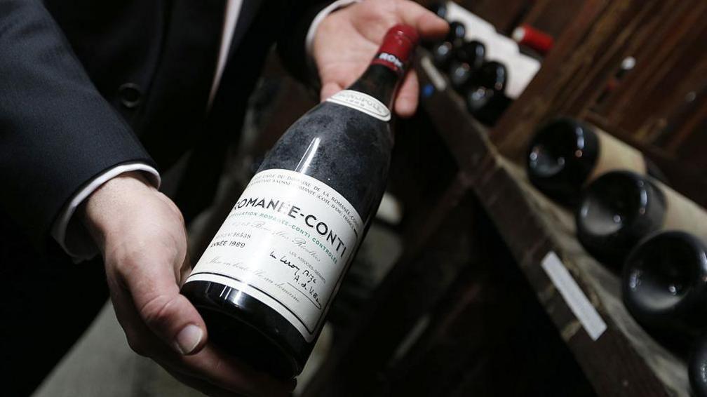 A man holding a bottle of very expensive red Burgundy