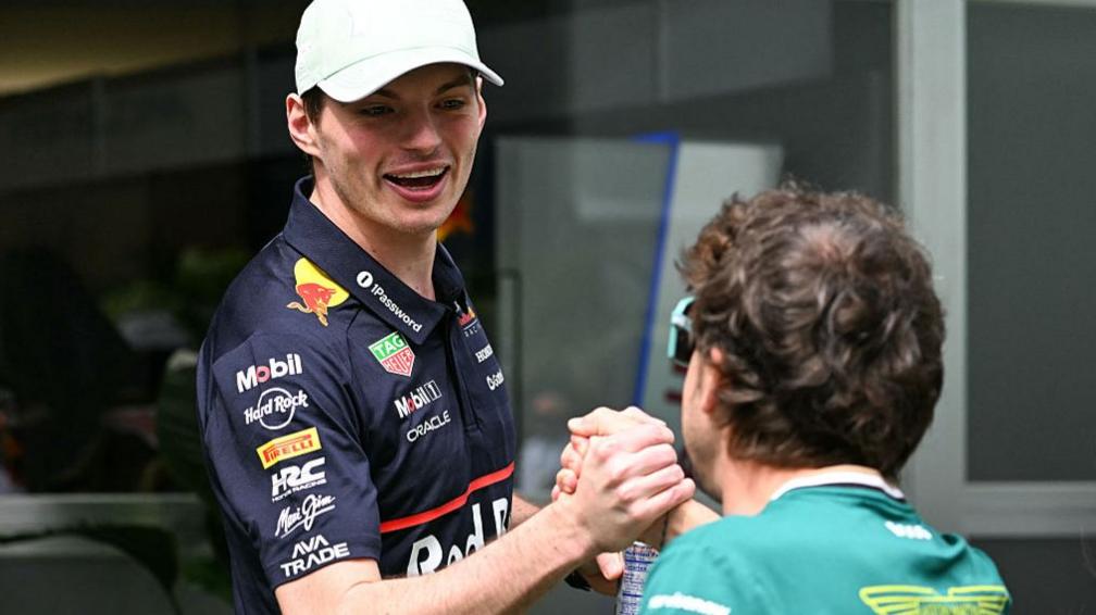 Fernando Alonso clasps Max Verstappen's hands as he congratulates him after the birth of his first child