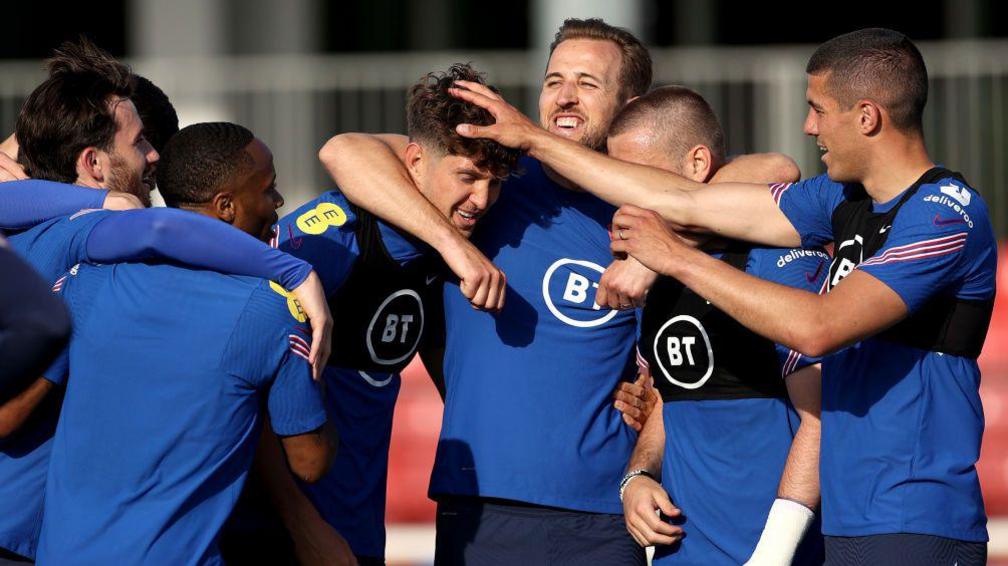 England players form in a huddle to give John Stones a playful headlock and a tousle of his hair