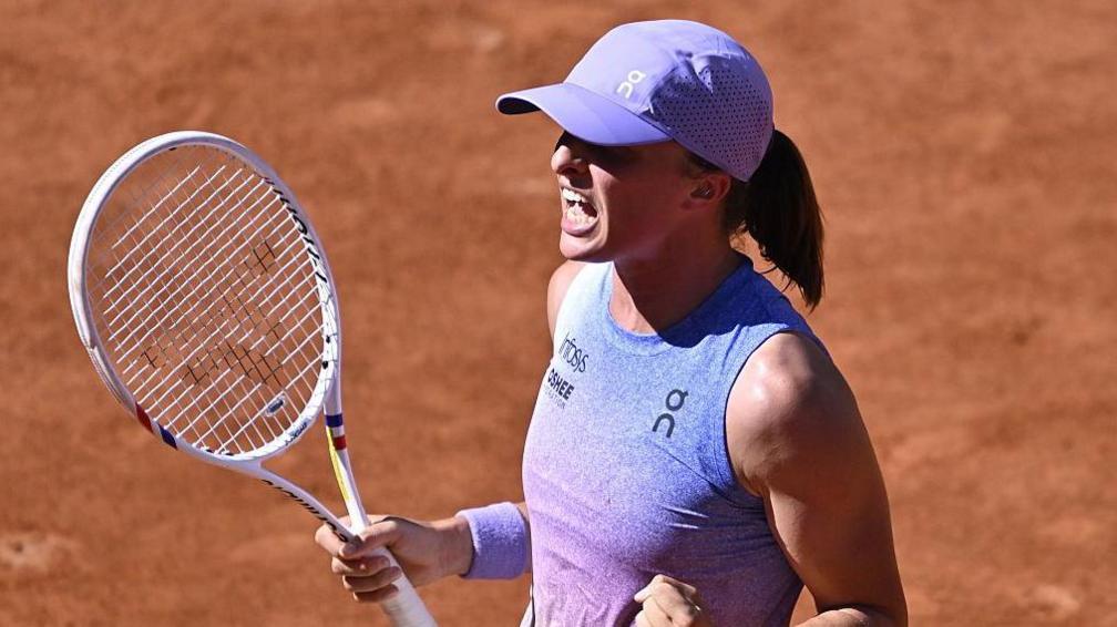 Iga Swiatek holds a tennis racquet