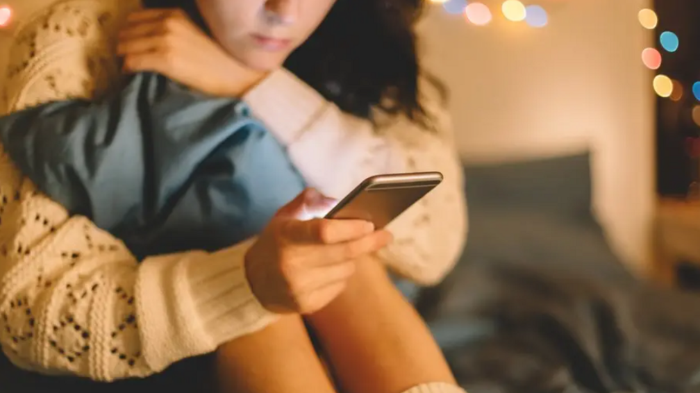 A generic images of an unidentifiable girl sitting on a floor looking at her phone