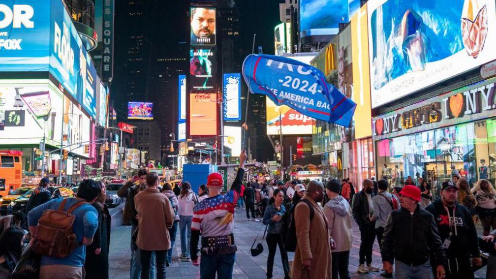 A pro-Trump supporter holds a banner in Times Square on election day, 5 November in New York City. 