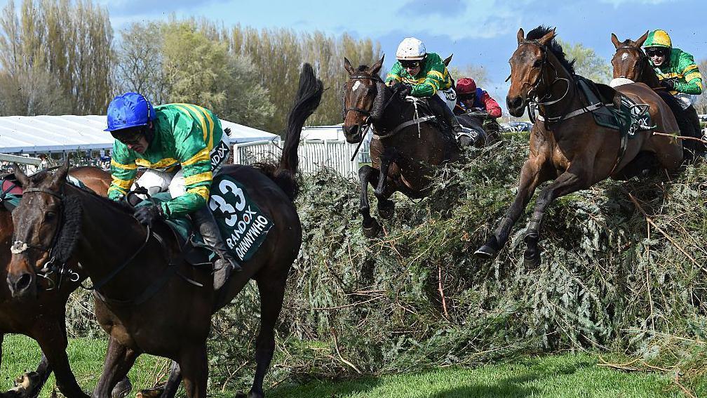 Horses jump one of the Grand National fences in the 2026 race