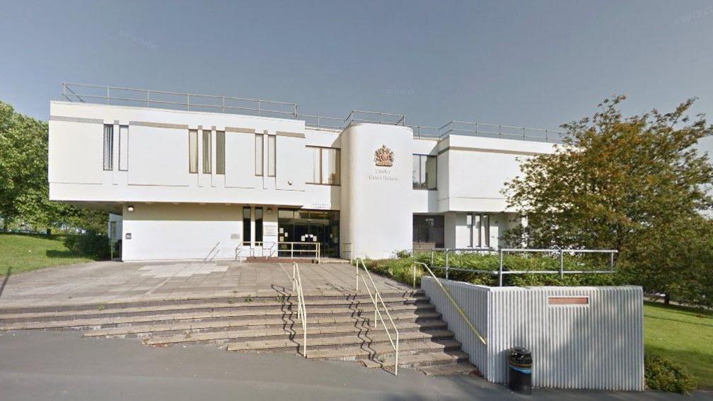 A white building with steps leading up to it and trees on either side