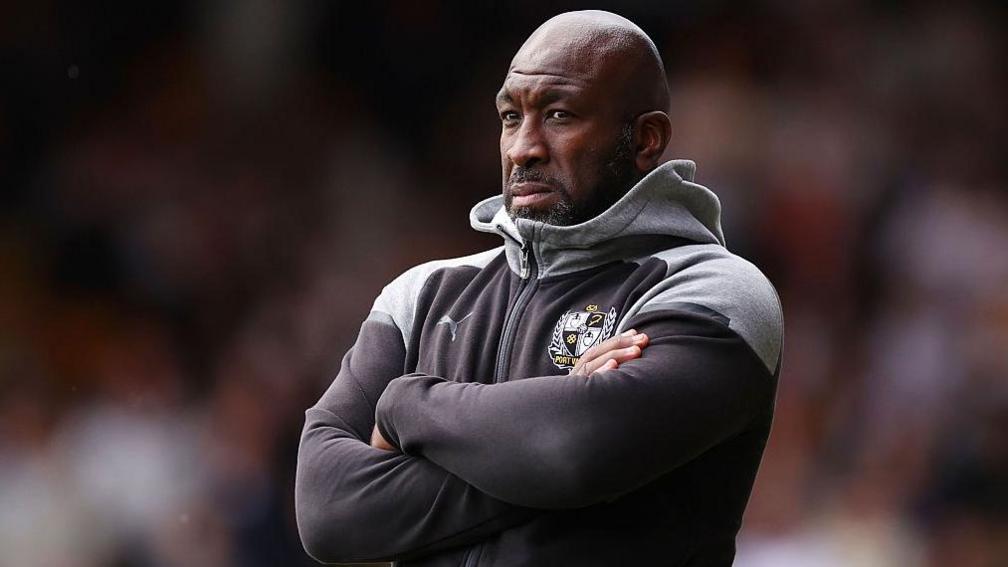 Port Vale manager Darren Moore stands with arms folded looking on during a match
