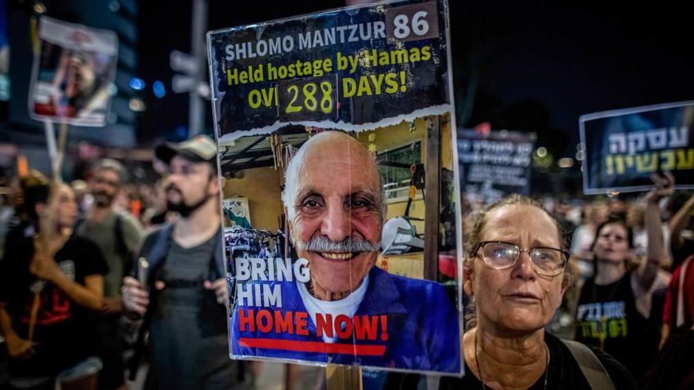  An Israeli woman holds a placard showing Shlomo Mantzur 