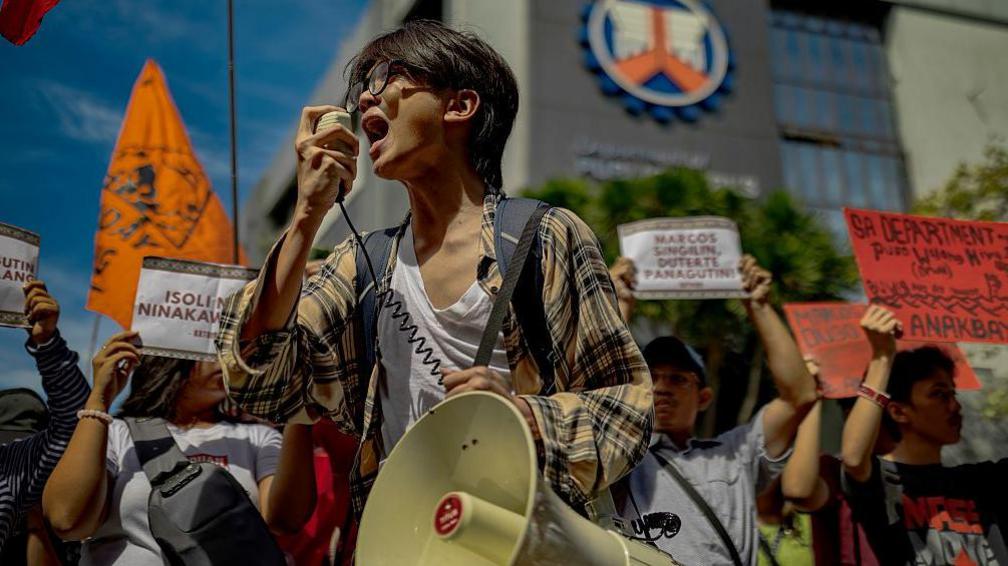A young protester in the Philippines speaks through a megaphone in front of a crowd