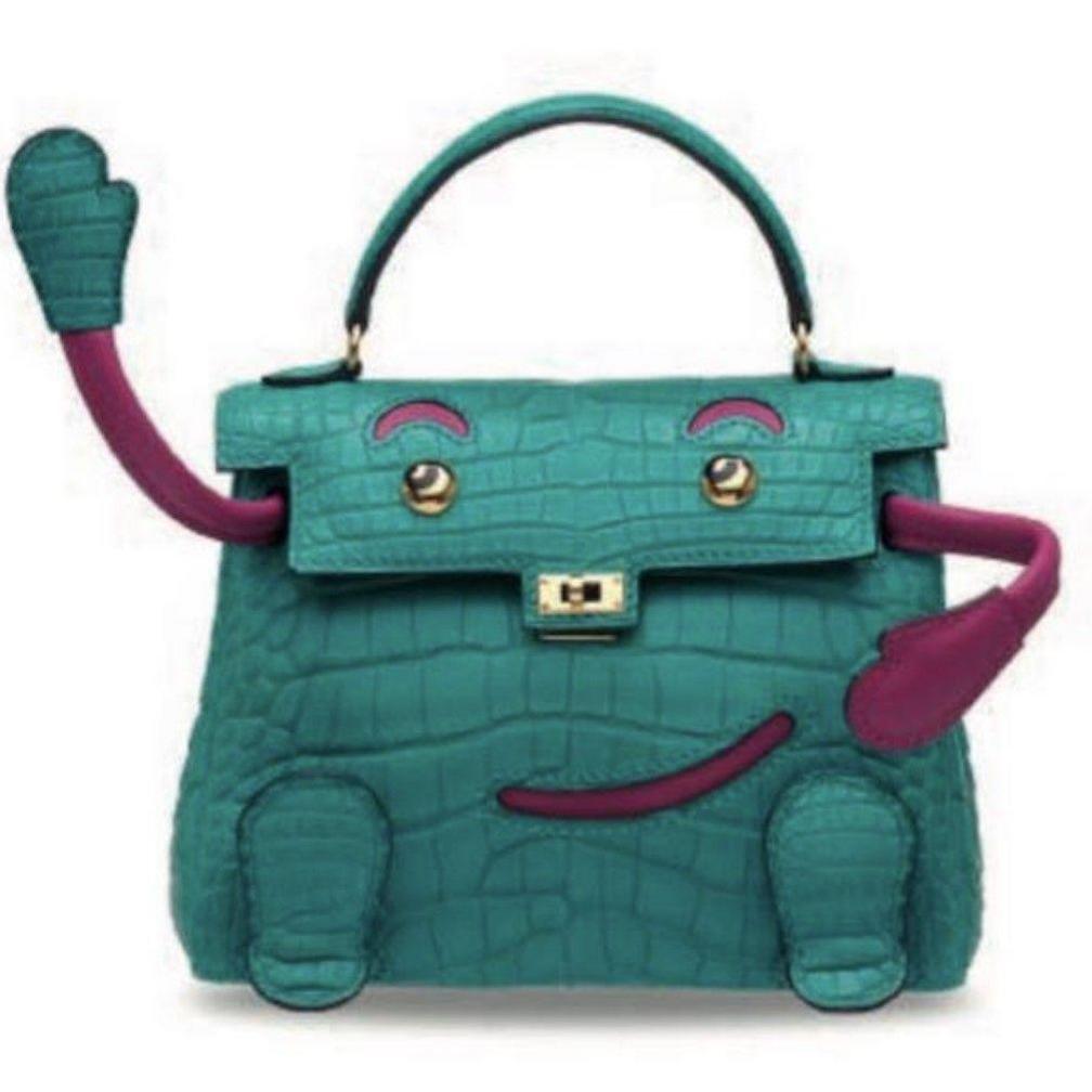 A green crocodile skin handbag with red arms and a smiley face as part of the design. 