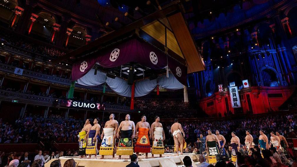 Rikishi perform a ring-entering ceremony wearing colourful aprons