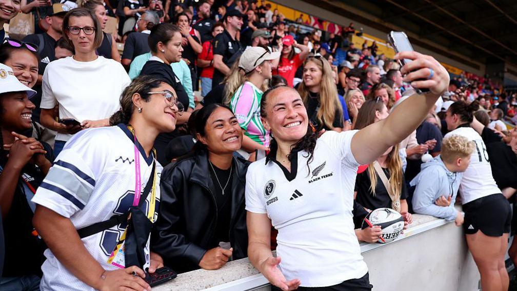 Portia Woodman Wickliffe takes a photo with a fan