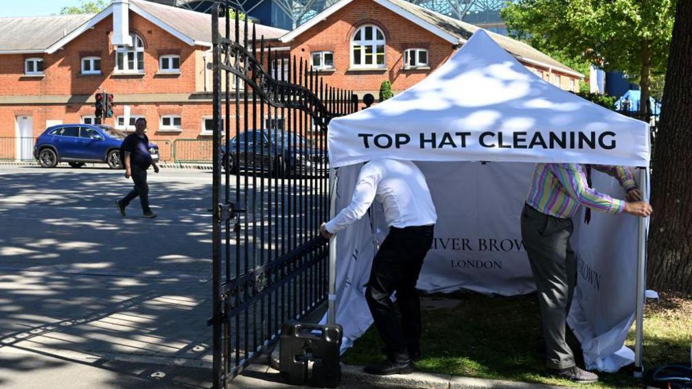 two men putting up a tent that reads "top hat cleaning"