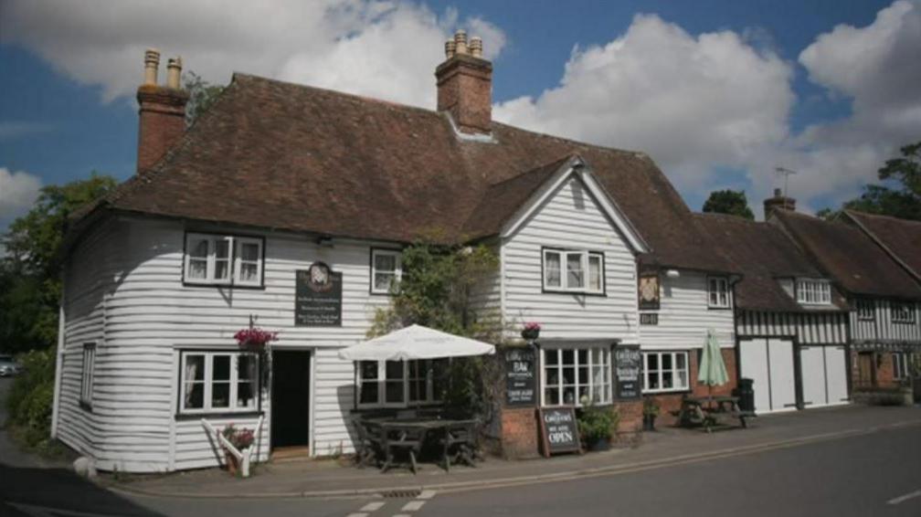 An exterior shot of the front of the Chequers Inn in Smarden with a thatched roof and white wooden panel exterior