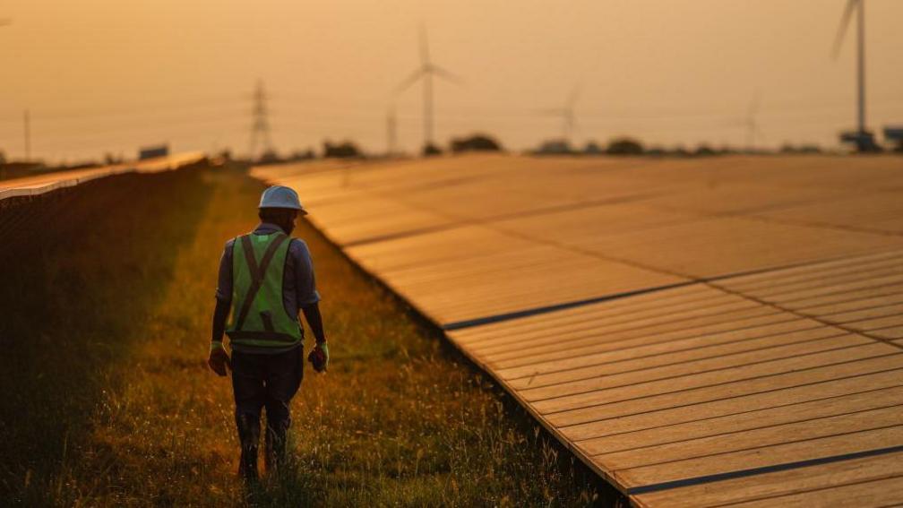 A maintenance worker inspects solar panels at a solar power plant operated by Ayana Renewable Power Pvt. in Tuticorin, India, on Wednesday, March 20, 2024. 