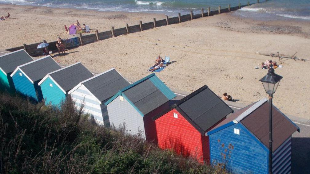 A row of different coloured huts facing Cromer beach during the summer