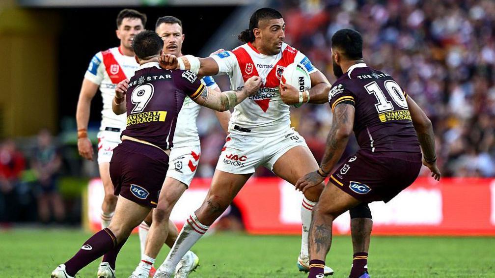 A charging Emre Guler fends off a Brisbane Broncos defender during a match in May