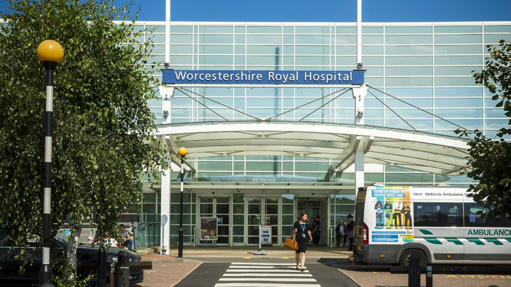 The outside of Worcestershire Royal Hospital woth a Silver ambulance parked on the right hand side of the building 