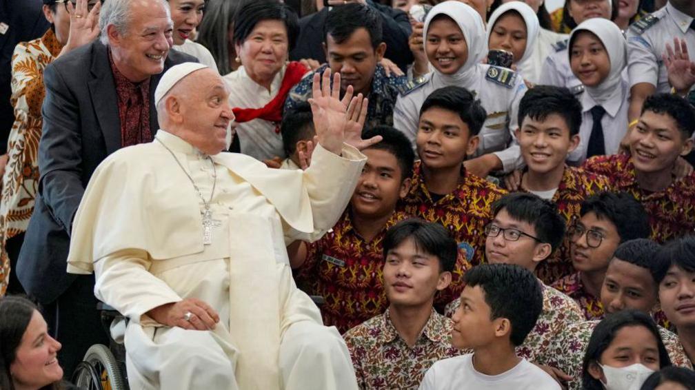 Pope Francis (4L) waves to people as Jose Maria del Corral, the President of Scholas Occurrentes (3L) watches at the Grha Pemuda Youth Centre in Jakarta on September 4, 2024.