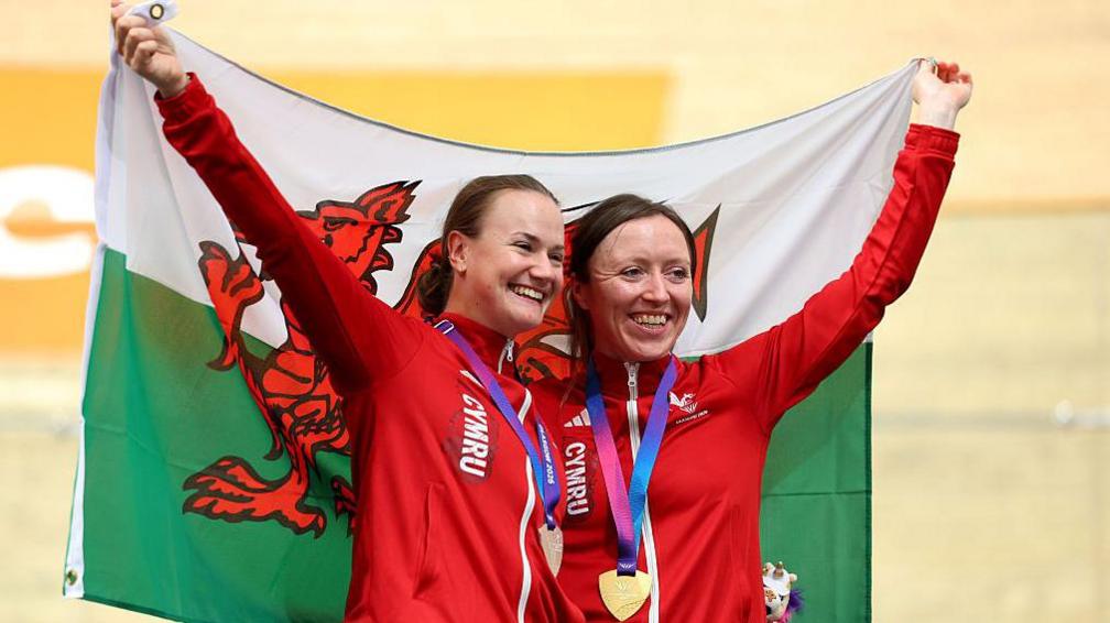 Anna Morris and Jess Roberts with medals and Welsh flag draped around them
