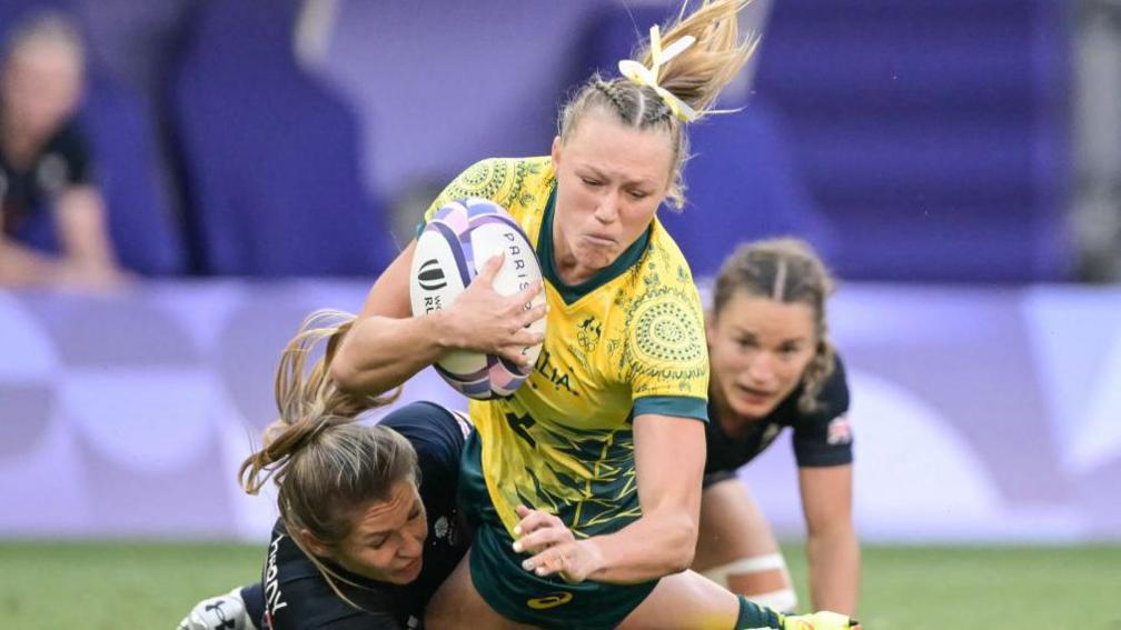 Australia's Maddison Levi (C) is tackled by Britain's Amy Wilson Hardy