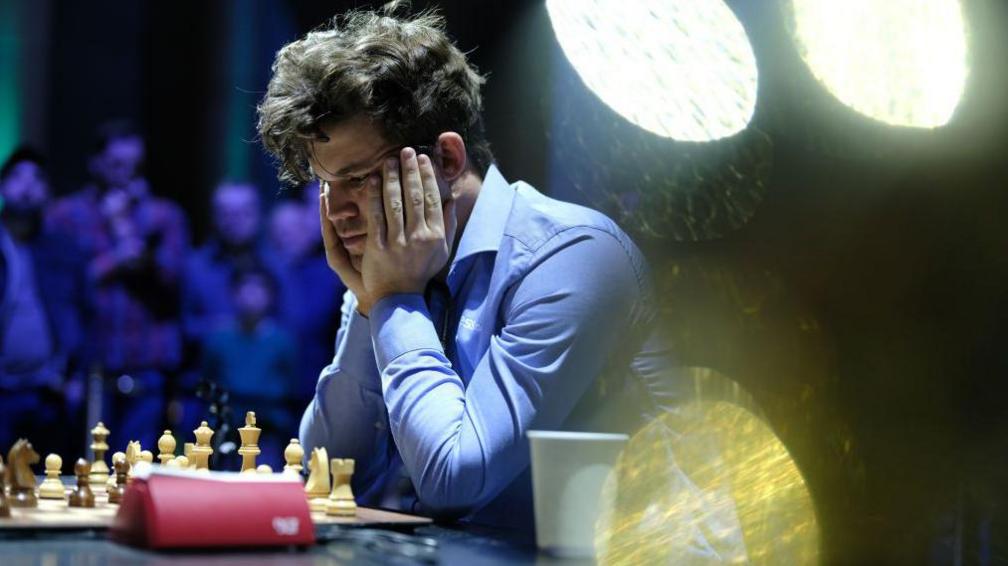 Magnus Carlsen holds his head in his hands as he looks at a chess board at the New York championships