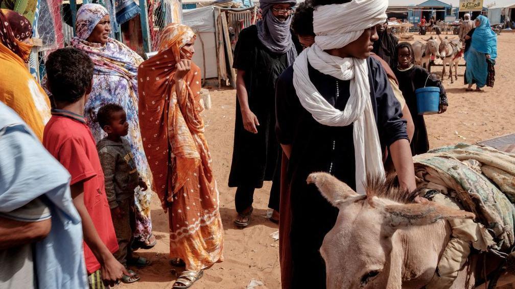 Men, women and children are seen at a refugee camp in Mauritania, with their livestock (7 June 2022)