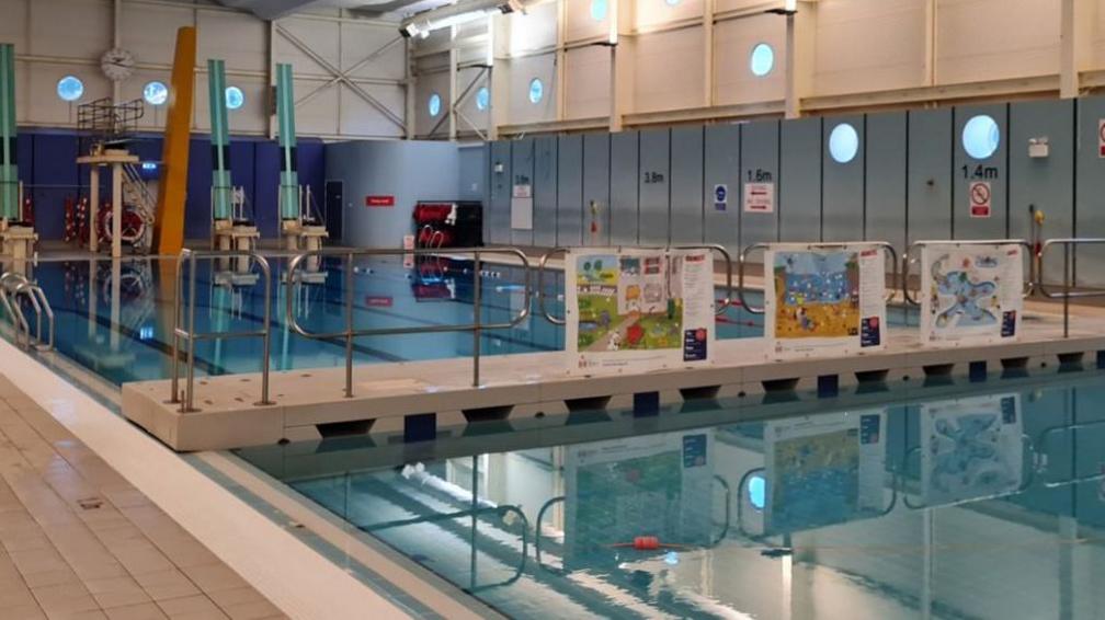An indoor swimming pool with no people in the water or on the surrounding edges.