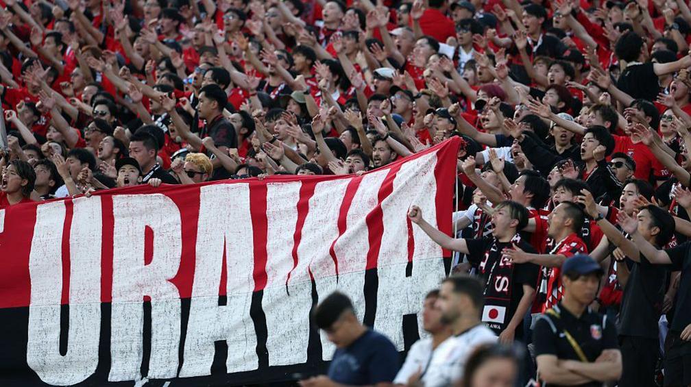 Urawa Reds fans hold up a giant banner while chanting for their team