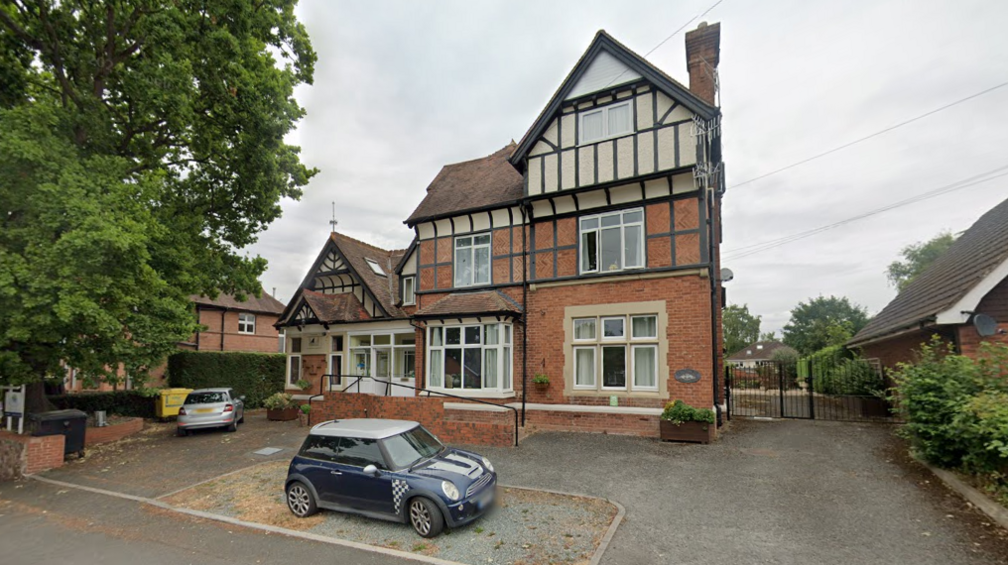 A three storey Edwardian house pictured with a blue Mini Cooper parked outside it.