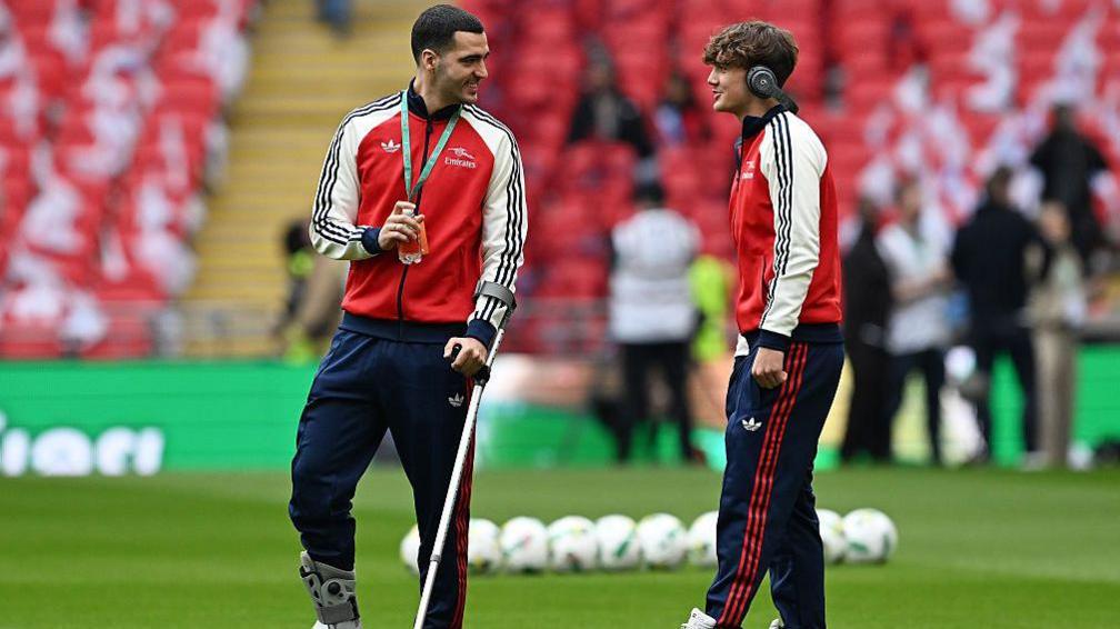 Mikel Merino of Arsenal inspects the pitch whilst on crutches alongside team mates Max Dowman prior to the Carabao Cup Final match between Arsenal and Manchester City at Wembley Stadium on March 22, 2026 in London, England.